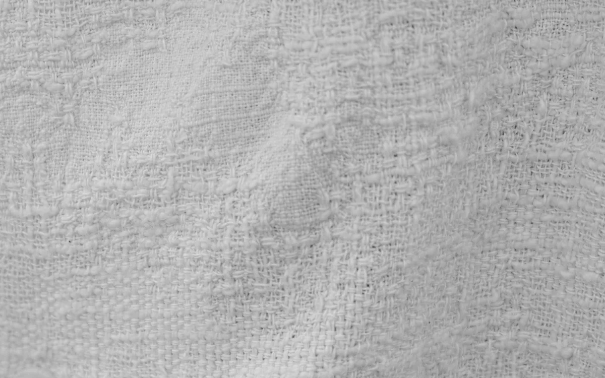 Folded bedding fabrics on a bed being inspected for weave and texture