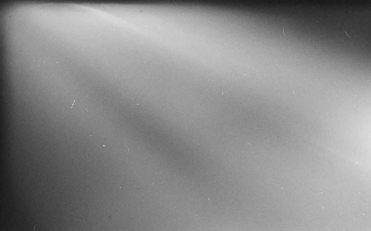 A close view of light leaking around a window shade and curtain panel