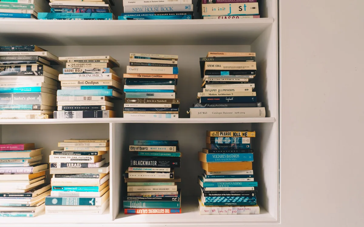 A person arranging books and a tray on a coffee table in a small living space