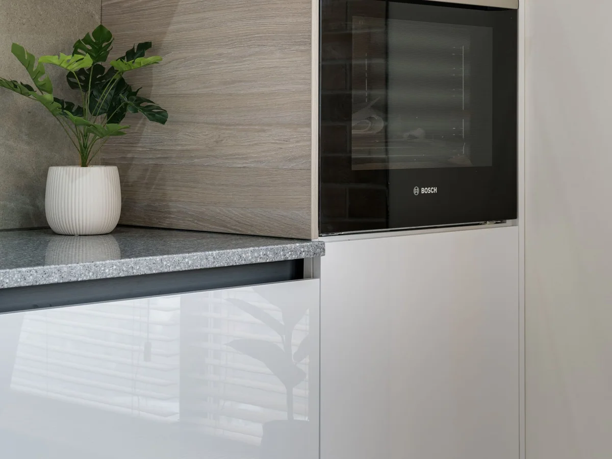 A countertop ice maker beside a glass of iced drinks in a small kitchen