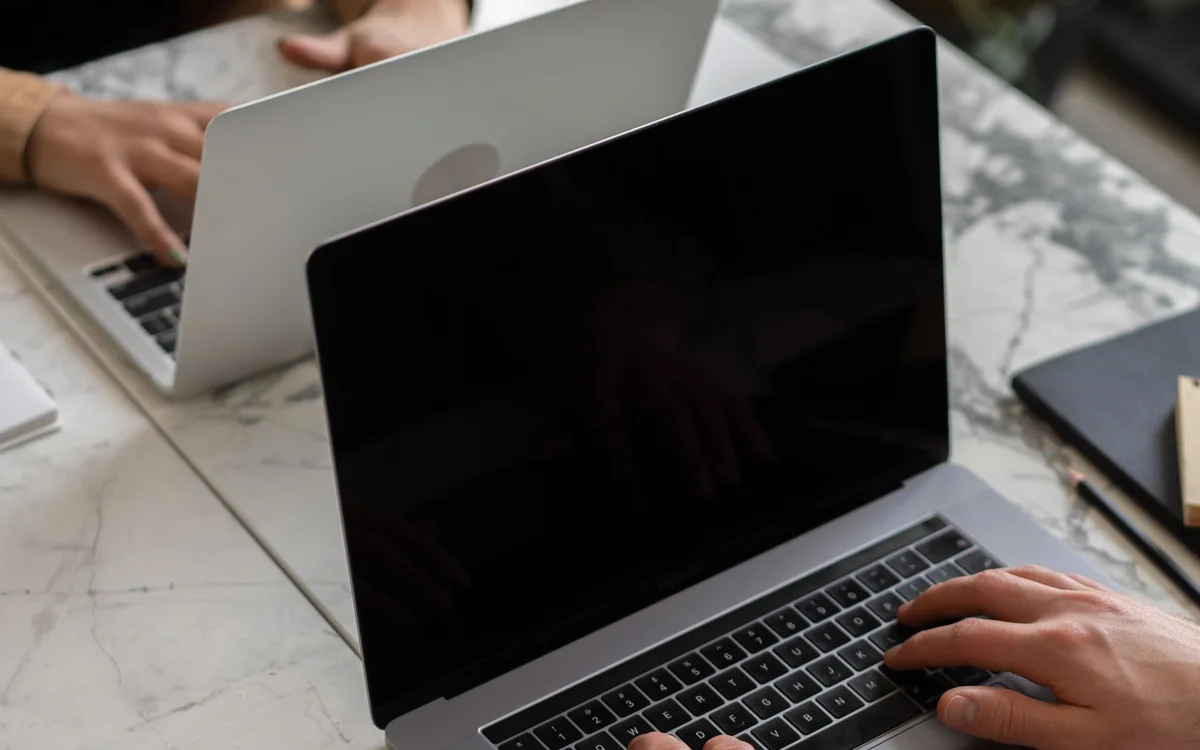 A person adjusting a small diffused light beside a laptop camera