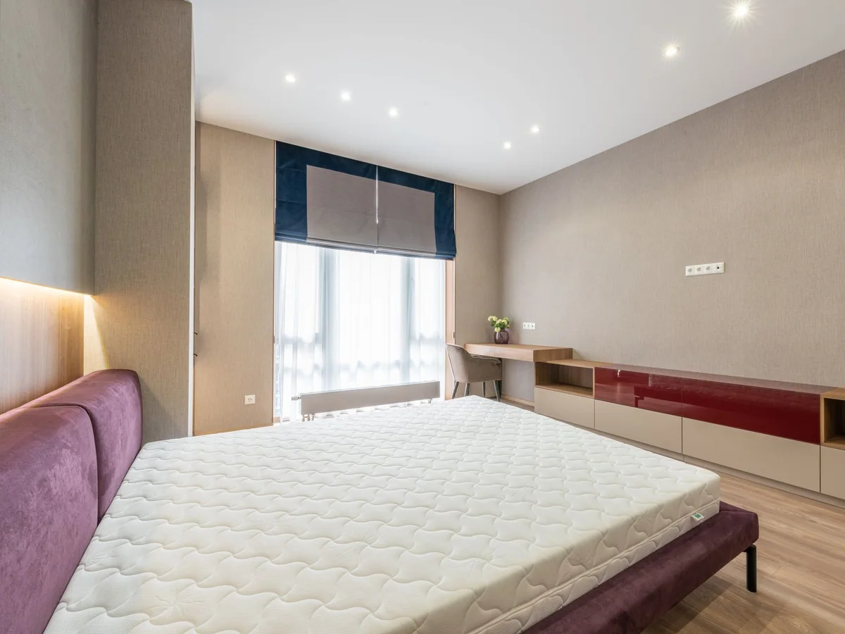 A mattress protector being fitted to a bed in a clean family bedroom