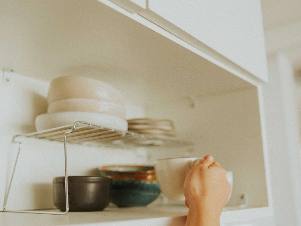 A deep pantry shelf organized with clear bins, jars, and labeled food groups