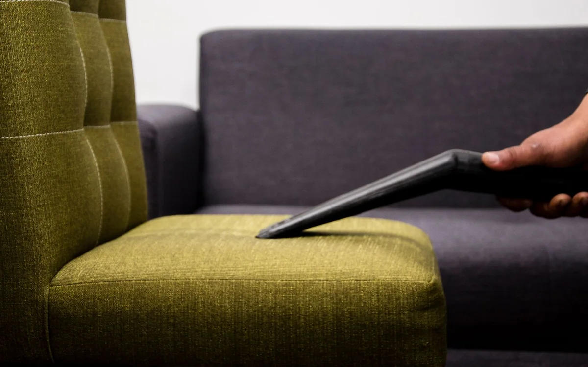 A close view of upholstery fabric and a hand-held lint brush on an accent chair