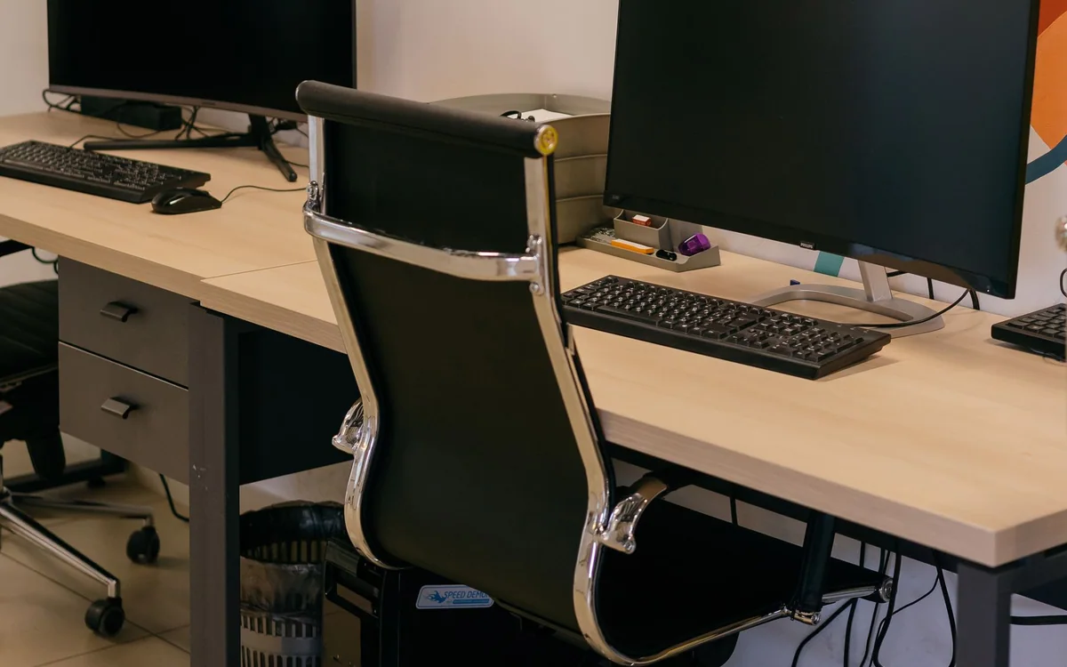 A person attaching a cable tray and power strip under a standing desk