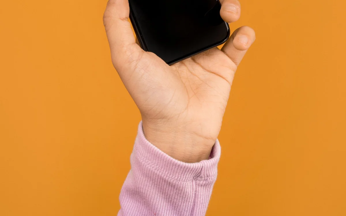 A hand comparing two light bulb colors in a home lighting fixture